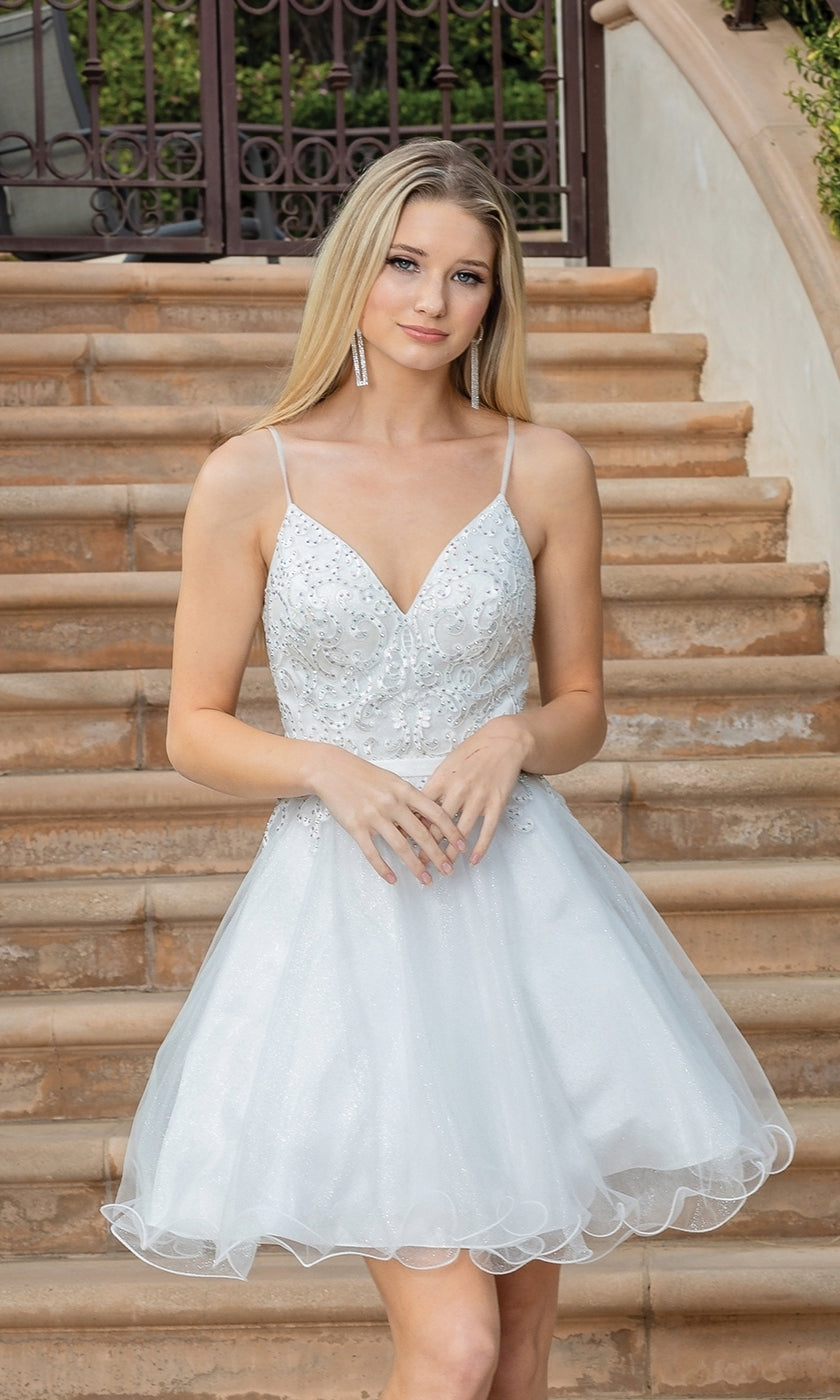 A woman wears the Lace-Up-Back Short Babydoll Homecoming Dress 3315—white, sleeveless, semi-formal with a fitted bodice and flared skirt—while standing on outdoor stone steps.